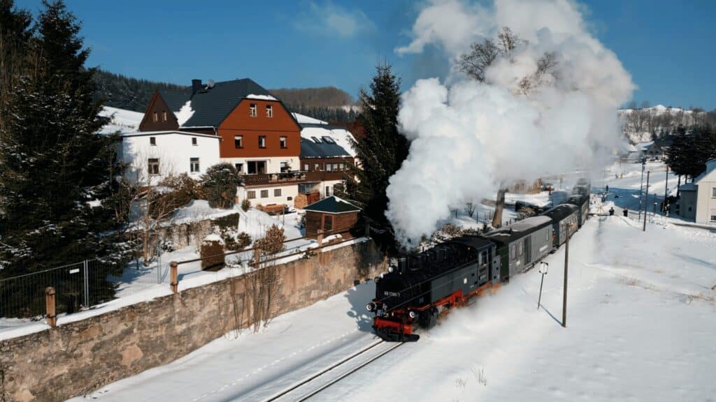 Fichtelbergbahn im Winter vor dem verschneiten Ferienhaus